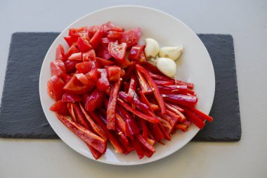 beyaz plaka üzerinde sarımsak ile taze kırmızı acı biber ve domates dilimleri, yakın çekim 