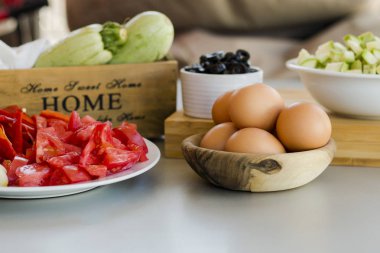 mutfak masasında kaselerde zeytin ile dilimlenmiş sebze ve yumurta ile tabaklar, pişirme süreci kavramı 