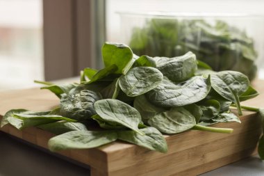 Mutfak tahtasının üzerinde bebek ıspanak yaprağı