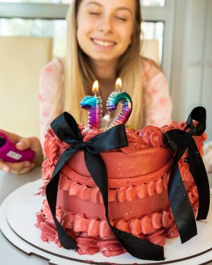 Mutlu 12 yaşındaki kız doğum gününü pasta ve mumlarla kutluyor.