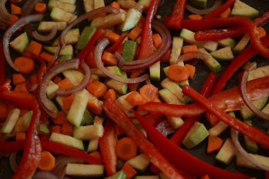 Bir demet renkli sonbahar sebze kabağı, kırmızı biber, ve fırın tepsisine serpiştirilmiş havuç, zeytinyağı ve bitkilerle serpilmiş, kızartılmaya hazır.