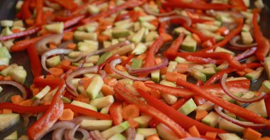 Bir demet renkli sonbahar sebze kabağı, kırmızı biber, ve fırın tepsisine serpiştirilmiş havuç, zeytinyağı ve bitkilerle serpilmiş, kızartılmaya hazır.