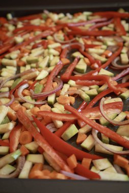 Bir demet renkli sonbahar sebze kabağı, kırmızı biber, ve fırın tepsisine serpiştirilmiş havuç, zeytinyağı ve bitkilerle serpilmiş, kızartılmaya hazır.