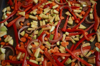 Bir demet renkli sonbahar sebze kabağı, kırmızı biber, ve fırın tepsisine serpiştirilmiş havuç, zeytinyağı ve bitkilerle serpilmiş, kızartılmaya hazır.