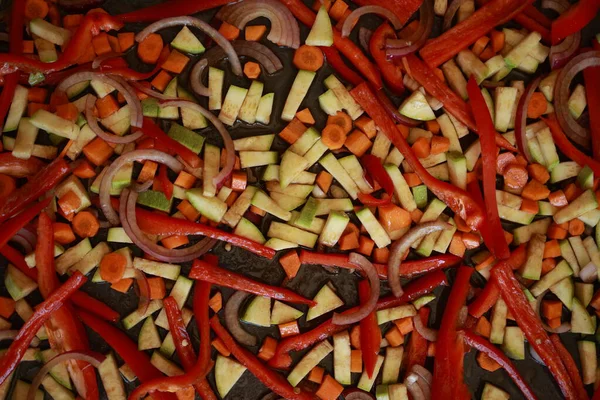 Bir demet renkli sonbahar sebze kabağı, kırmızı biber, ve fırın tepsisine serpiştirilmiş havuç, zeytinyağı ve bitkilerle serpilmiş, kızartılmaya hazır.