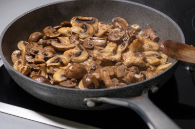 sliced mushrooms and onions sizzling in a hot pan