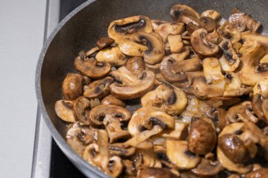 sliced mushrooms and onions sizzling in a hot pan