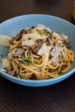 creamy pasta dish topped with savory mushroom sauce, grated parmesan, and fresh thyme, served in a blue bowl