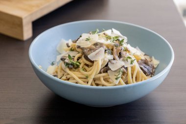 creamy pasta dish topped with savory mushroom sauce, grated parmesan, and fresh thyme, served in a blue bowl