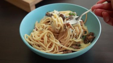 Taze pişmiş spagetti kremalı mantar sosuna atılmış, mavi bir kasede servis edilmiş ve yemeye hazır.