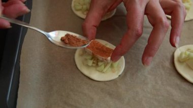 Eller peynirli mini turtalar, taze elma dilimleri ve puf börekleri hazırlıyor.