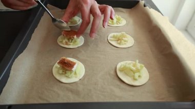 Eller peynirli mini turtalar, taze elma dilimleri ve puf börekleri hazırlıyor.