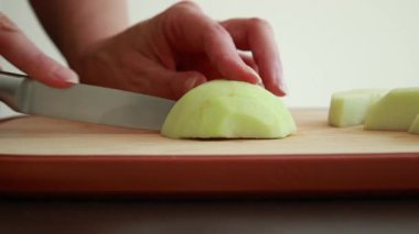 Kadın eli kesme tahtasındaki taze, çıtır yeşil elmayı kesiyor.