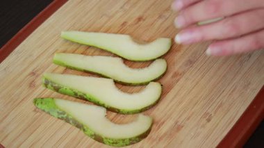 Taze armut dilimleri düzgünce sade bir ahşap kesme tahtasına yerleştirilmiş.