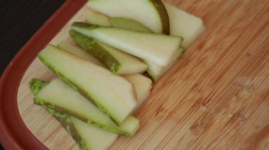 Taze armut dilimleri düzgünce sade bir ahşap kesme tahtasına yerleştirilmiş.