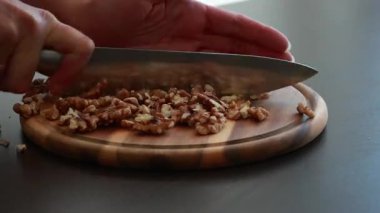 Kadınların elleri yuvarlak ahşap bir tahtanın üzerinde taze ceviz kesiyor.