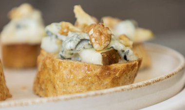 Taze armut dilimleri ve kremalı mavi peynirle kaplı çıtır crostini. Zarif sonbahar aperatifleri ve bayram partisi atıştırmalıkları için mükemmel.