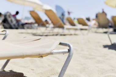 bazı bej güneşlenme sandalyeli ve La Barceloneta Beach, Barselona, İspanya, tanınmayan insanlar arka planda güneşlenme ile bej birkaç şemsiye closeup