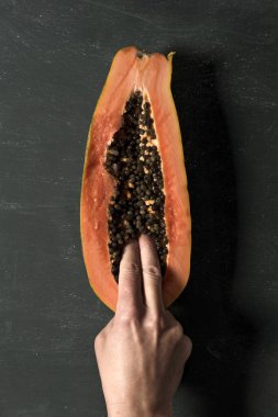 yüksek açı çekim içine bir papaya, Genç bir beyaz adam parmakları kesilmiş yarısında, koyu yeşil arka plan üzerinde