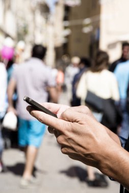 Genç bir beyaz adam bir kalabalık yaya sokakta bir smartphone kullanarak closeup
