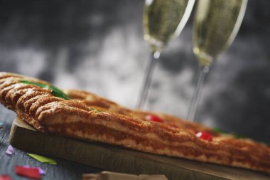 closeup coca de Sant Joan, şampanya, havai fişek ve konfeti ile gözlük yanındaki rustik bir tablo Saint Johns arifesinde yenen Catalonia, İspanya, tipik bir tatlı düz pasta