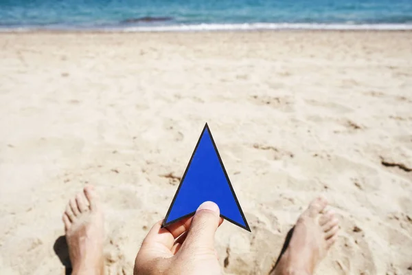 特写一个年轻的白人男子与蓝色箭头在他的手上的标志 在海滩上放松 在背景海 — 图库照片