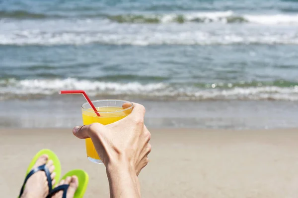 해변에서 상쾌한 오렌지 잔으로 슬리퍼 켤레를 남자의 — 스톡 사진