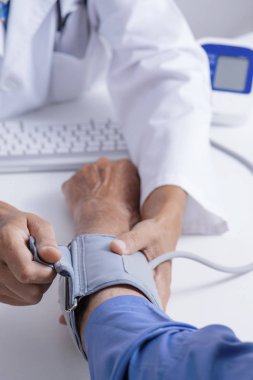 yaklaşık bir tansiyon aleti ile üst düzey bir beyaz hasta adamın kan basıncı ölçmek için bir beyaz doktor adam, beyaz bir ceket, closeup