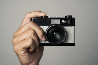 tatlı obserever için yaklaşık bir off-beyaz arka plan karşı Obtüratör butonuna basın işaret eden beyaz bir adamın elinde bir retro film kamerası ile