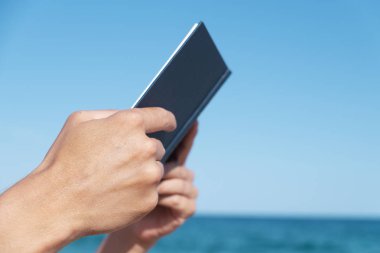 tatlı genç bir beyaz adam sahilde bir kitap okuma