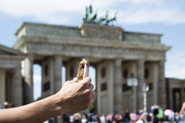 Genç bir beyaz adam, Berlin, Almanya popüler Brandenburg Kapısı önünde bir sandviç yeme closeup