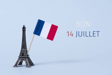 bir minyatür Eyfel Kulesi, bir Fransız bayrağı ve metin bon 14 juillet, 14 Temmuz, uçuk mavi arka plana karşı Fransızca olarak yazılmış Fransa'nın ulusal günü kutlu olsun