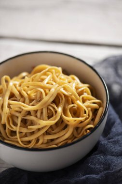 closeup beyaz seramik kase yakisoba erişte, sebze ve bir beyaz rustik ahşap masa üzerinde yakisoba sos ile