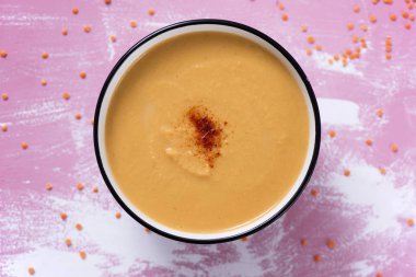 kırmızı biber, pembe ve beyaz ahşap rustik bir masa üzerinde bir beyaz seramik kase kabak ve Hindistan cevizi püresi ile yüksek açı görünümünü serpilir