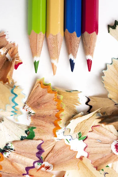 在白色背景下 不同颜色的铅笔蜡笔和一堆不同颜色的扇形刨花的高角度视图 — 图库照片