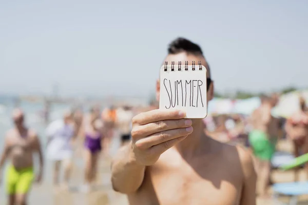 特写一个赤裸的年轻白种人在海滩上显示一个螺旋记事本 与文本夏天手写在第一页 — 图库照片