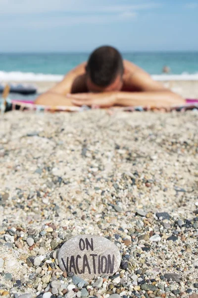 Zbliżenie Kamienia Tekstem Wakacjach Nim Napisane Piaszczystej Plaży Młody Człowiek — Zdjęcie stockowe