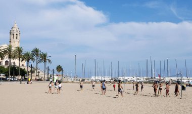 Sitges, İspanya - 27 Temmuz 2018: Platja de la Fragata voleybol oynayan insanlar plaj Sitges, İspanya'Sant Bartomeu vurgulayarak, ben Santa Tecla Kilisesi arka planda