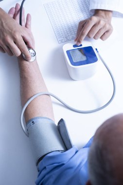 kan basıncı ve nabız üst düzey bir beyaz hasta adamın bir tansiyon aleti ve bir steteskop ile ölçme ile beyaz bir ceket, bir beyaz doktor adam closeup