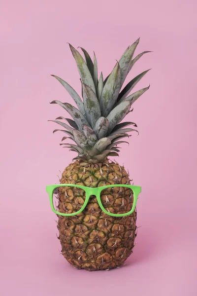 在粉红色背景上戴着一双霓虹灯绿色无透镜眼镜的菠萝特写 — 图库照片