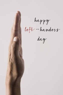 the left hand of a young man and the text happy left-handers day against a beige background clipart
