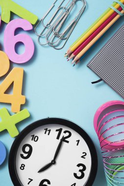 bir saat yedide, bazı kalem farklı renkteki boya, bir not defteri, bazı ataç ve orta bir boşluk ile mavi bir arka plan üzerinde farklı renklerde üç boyutlu bazı sayılar