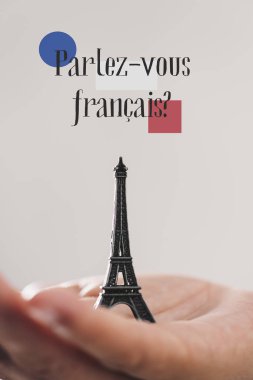 bir minyatür Eyfel Kulesi'ne bir genç adam ve soru parlez-vous francaise yandan Fransızca biliyor musun? Fransızca olarak yazılmış bir off-beyaz arka planı