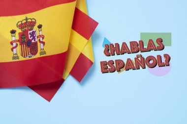 some flags of Spain and the question hablas espanol? do you speak Spanish? written in Spanish, on a blue background clipart