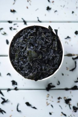 wakame, bir Asya yenilebilir yosun yeşil soluk rustik ahşap bir masa üzerinde beyaz bir seramik kase üzerinde miso çorbası gibi geleneksel Çorbalar kullanılan kurutulmuş yaprakları bir yığın yüksek açılı görünüş
