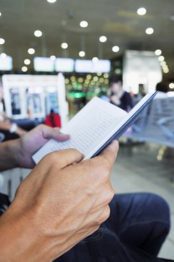 tatlı genç bir beyaz adam bir tren veya otobüs istasyonu veya bir havaalanı bekleme odasında bir kitap okuma