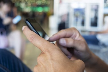 bir tren veya otobüs istasyonu veya bir havaalanı bekleme odasında bir akıllı telefon kullanan genç bir beyaz adam closeup
