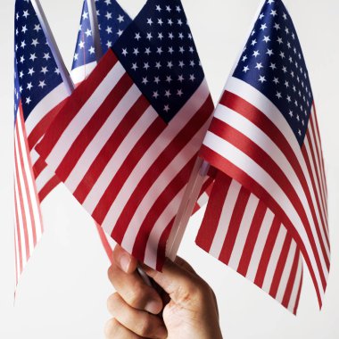 Genç bir beyaz adam elinde bir off-beyaz arka plan karşı bazı Amerikan bayrakları ile closeup