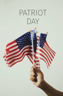 Genç bir beyaz adam elini ve metin vatansever gün, off-beyaz bir arka plan karşı bazı Amerikan bayrakları ile closeup