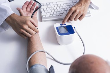 Tansiyon aleti ile üst düzey bir beyaz hasta adamın kan basıncı ölçme ile beyaz bir ceket, bir beyaz doktor adam closeup